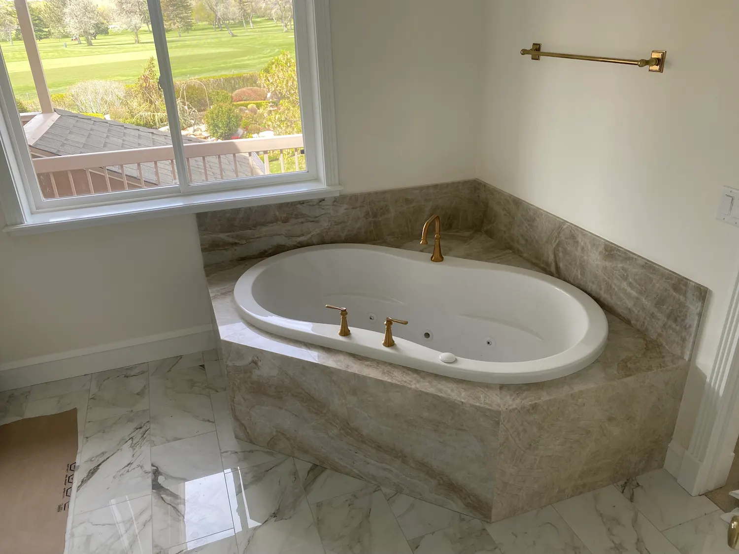 Marble soaking tub surround with gold fixtures